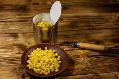 Açık konserve ve mısır ile plaka ve ahşap masa üzerinde açacağı olabilir