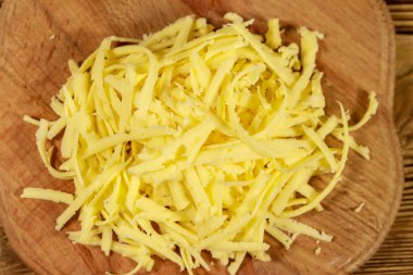 Ahşap masa üzerinde kesme tahtası üzerinde rendelenmiş peynir