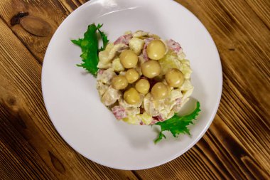 Ahşap masada marine mantar, sosis, soğan ve mayonez ile patates salatası