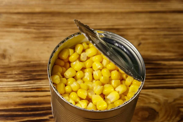 Open tin can of corn on wooden table — Stock Photo, Image