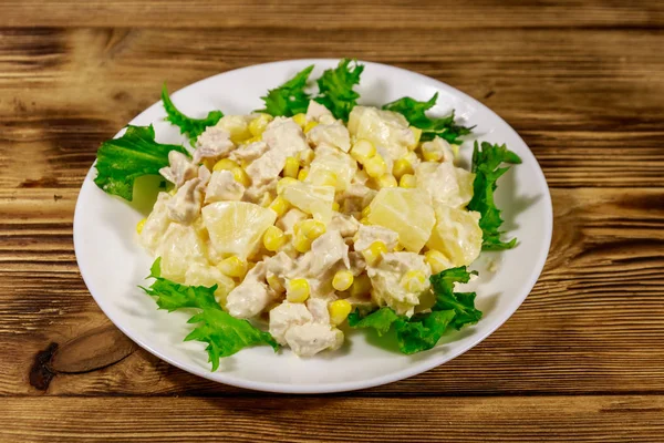 Праздничный салат с куриной грудью, сладкой кукурузой, консервированным ананасом и майонезом на деревянном столе — стоковое фото