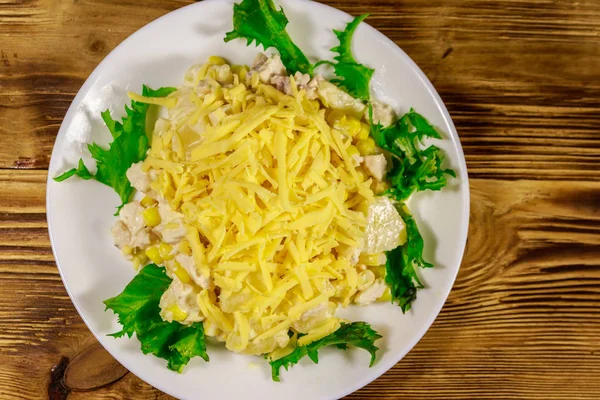 Праздничный салат с куриной грудью, сладкой кукурузой, консервированным ананасом, сыром и майонезом на деревянном столе — стоковое фото
