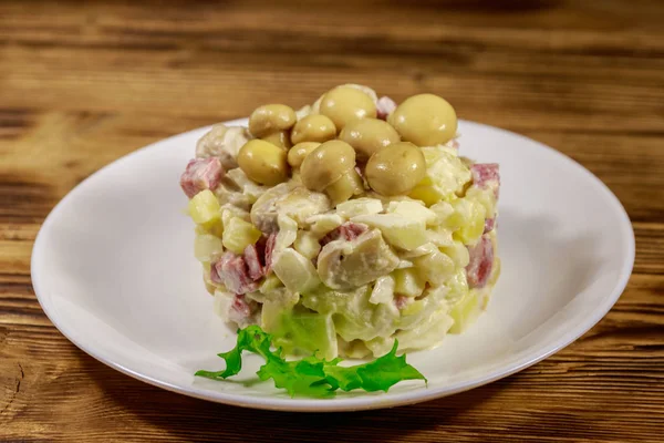 Картофельный салат с маринованными грибами, колбасой, луком и майонезом на деревянном столе — стоковое фото