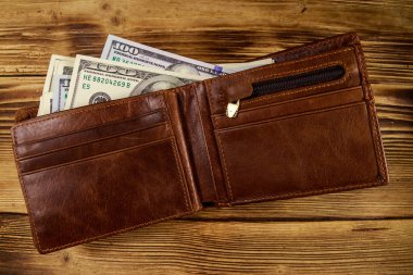 Ahşap masanın üzerinde Amerikan doları olan açık cüzdan. Üstte görüntü
