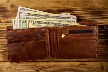 Ahşap masanın üzerinde Amerikan doları olan açık cüzdan. Üstte görüntü