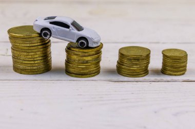 Beyaz ahşap arka plan üzerinde altın sikke yığınları üzerinde Minyatür araba modeli