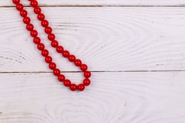 Beyaz ahşap arka planda kırmızı boncuk kolye. Üst görünüm