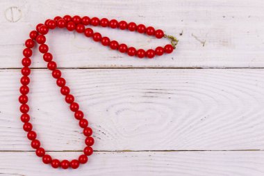 Beyaz ahşap arka planda kırmızı boncuk kolye. Üst görünüm