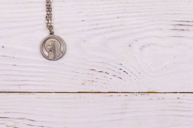 Beyaz ahşap arka plan üzerinde Bakire Meryem kolye. Üst görünüm, kopyalama alanı