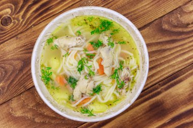 Tahta masada erişte ve sebze ile tavuk çorbası. Üstte görüntü