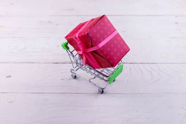 Beyaz ahşap arka plan üzerinde büyük hediye kutusu ile Alışveriş sepeti — Stok fotoğraf