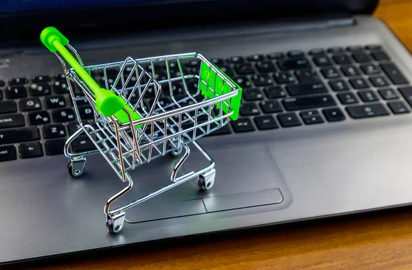 Concepto de compras online. Pequeño carrito de compras en el teclado portátil — Foto de Stock