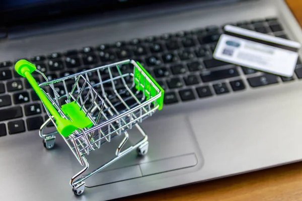 Concepto de compras online. Pequeño carrito de compras y tarjeta de crédito en el teclado portátil —  Fotos de Stock