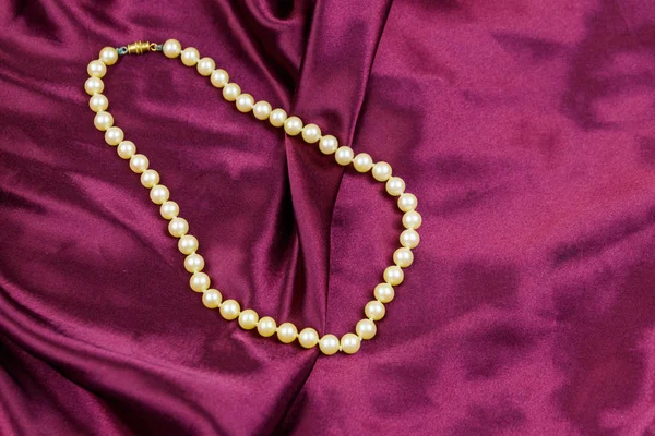 Perłowy naszyjnik na fioletowym tle tkaniny satynowej — Zdjęcie stockowe