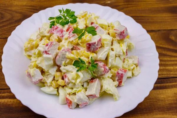 Салат с крабовыми палочками, сладкая кукуруза, китайская капуста, яйца и майонез на деревянном столе — стоковое фото