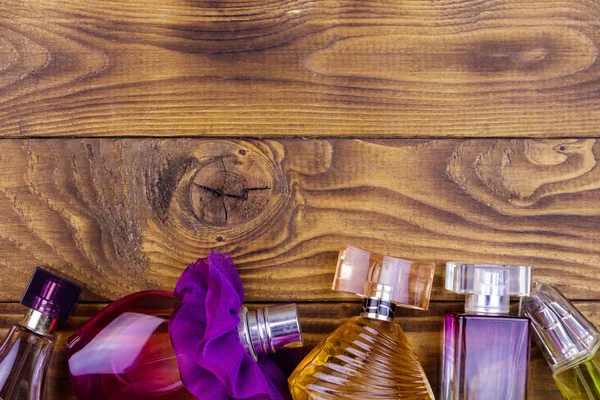 Different bottles of perfume on the wooden background. Top view