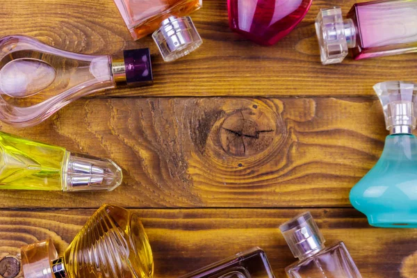 Different bottles of perfume on the wooden background. Top view — Stock Photo, Image