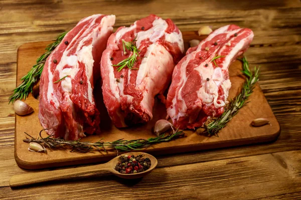 Raw pork ribs with spices, garlic and rosemary on wooden table — Stock Photo, Image