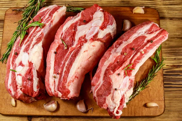 Baharatlı çiğ domuz kaburgası, sarımsak ve ahşap masada biberiye.. — Stok fotoğraf