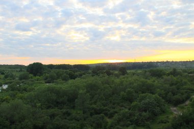 Yeşil tepeler ve ağaçlar üzerinde güzel turuncu gün batımı