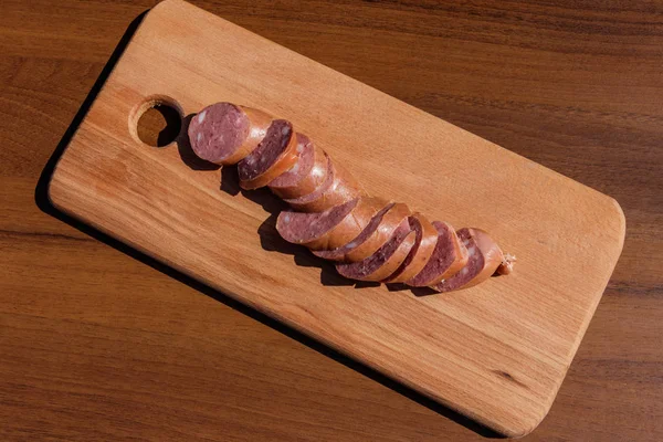 Räucherwurst auf einem Holzbrett auf einem Tisch — Stockfoto