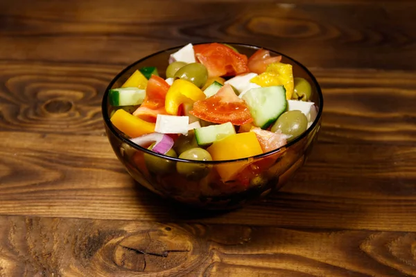 Salada grega em tigela de vidro na mesa de madeira — Fotografia de Stock