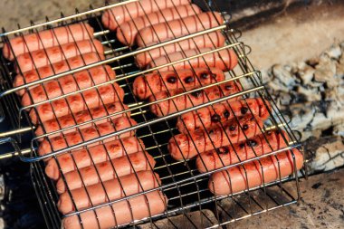 Kamp ateşinde ızgara sosis pişirmek. 