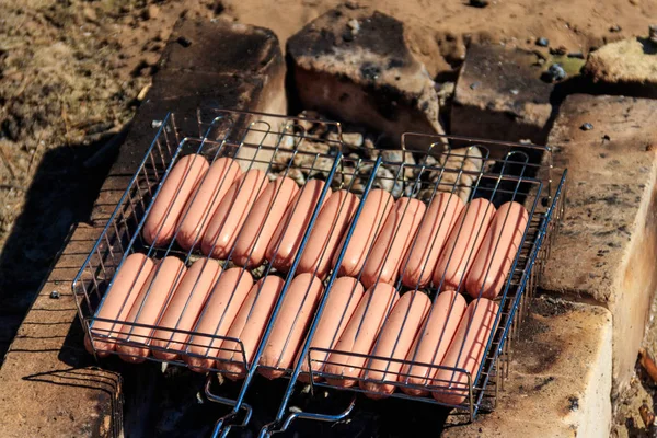 Griller les saucisses dans le barbecue cuire sur le feu de camp — Photo