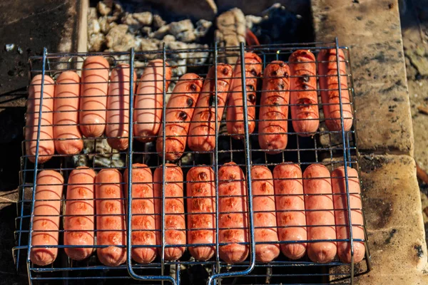 Griller les saucisses dans le barbecue cuire sur le feu de camp — Photo