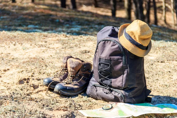 Mochila turística con botas de senderismo, sombrero, brújula y mapa en el claro en el bosque de pinos. Equipo de equipo de trekking. Concepto de viaje —  Fotos de Stock