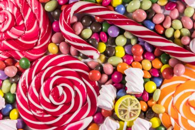 Renkli çikolata şekerlemeleri, lolipoplar, şeker kamışı ve şekerlemelerin arka planı