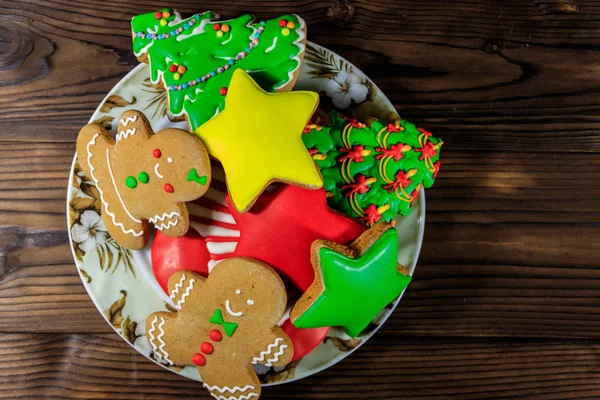 จานกับคุกกี้ขนมปังขิงเทศกาลคริสต์มาสอร่อยในรูปของต้นคริสต์มาส, คนขนมปังขิง, ดาวและถุงน่องคริสต์มาสบนโต๊ะไม้. ท็อปวิว — ภาพถ่ายสต็อก