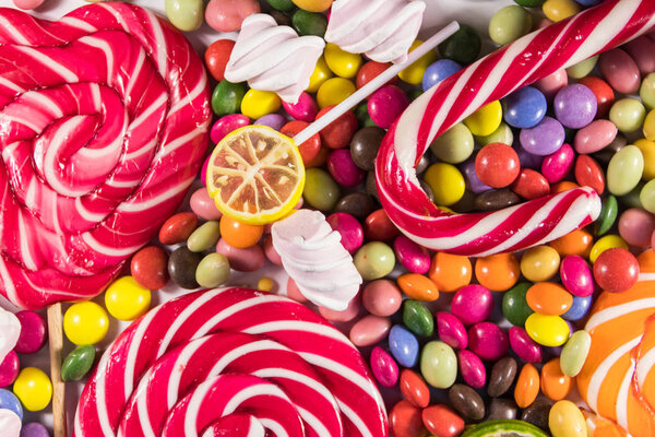 На фоне красочных шоколадных конфет, леденцов, конфет и зефира