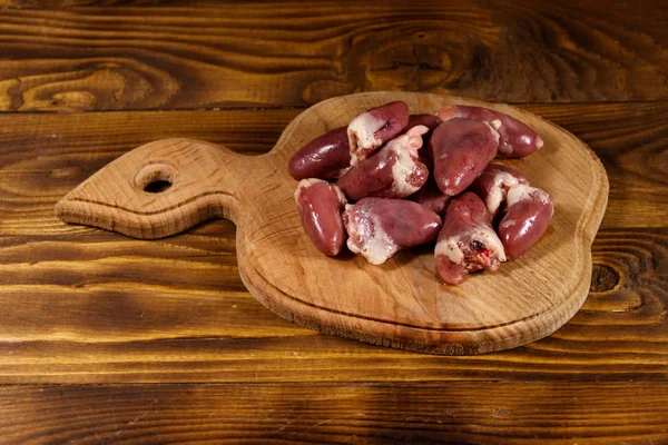 Сирі курячі серця на обробній дошці на дерев'яному столі — стокове фото