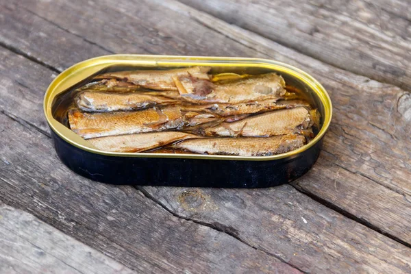 Open tin can of sprats on rustic wooden table — Stock Photo, Image