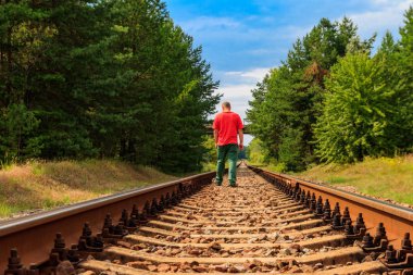 Yalnız adam tren yolunda yürüyor.