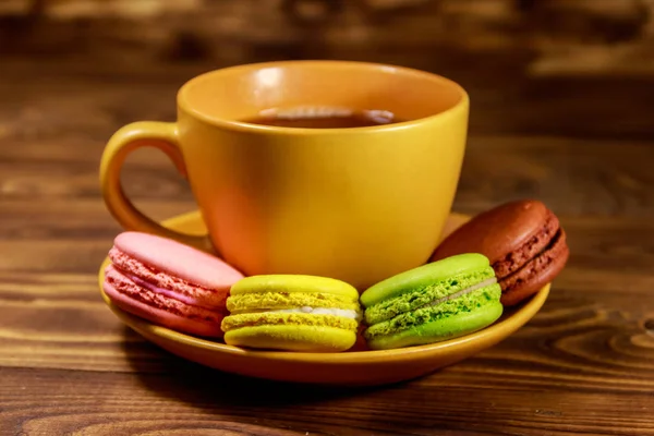 Tasse Kaffee mit leckeren bunten Macarons auf Holztisch — Stockfoto