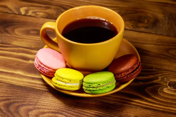 Cup of coffee with tasty colorful macarons on wooden table — Stock Photo, Image