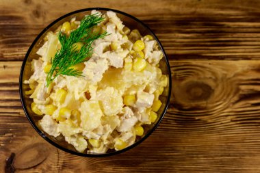 Tavuk göğsü, tatlı mısır, konserve ananas, peynir ve ahşap masada mayonez ile Şenlikli salata