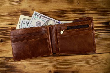 Ahşap masanın üzerinde Amerikan doları olan açık cüzdan. Üstte görüntü