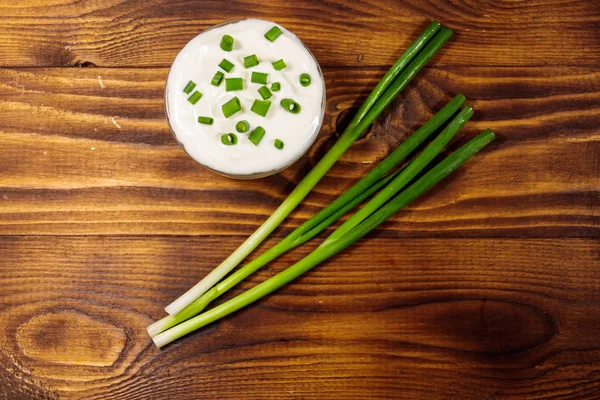 Sour cream and green onion on wooden table. Top view — Stock Photo, Image