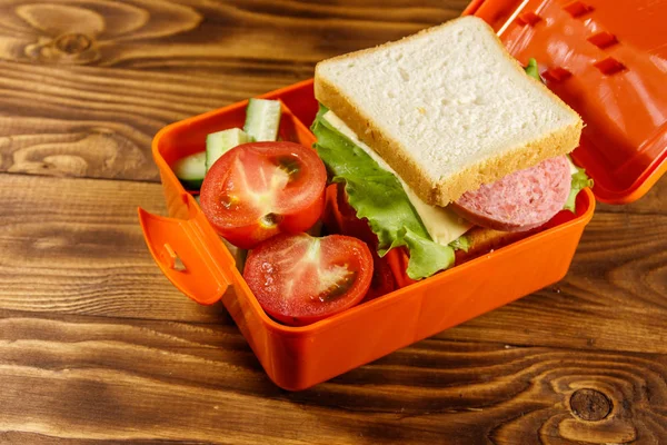 School lunch box with sandwich and fresh vegetables on wooden table — Stock Photo, Image