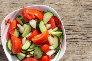 Domates, salatalık, soğan ve zeytin yağı ahşap masa üzerinde taze sebze salatası. Üstten görünüm