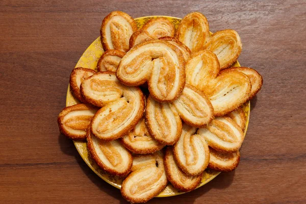 Palmier koekjes-Franse koekjes gemaakt van bladerdeeg (ook wel Palm bladeren, olifant oren of Franse harten) in een bord op houten tafel. Top View — Stockfoto