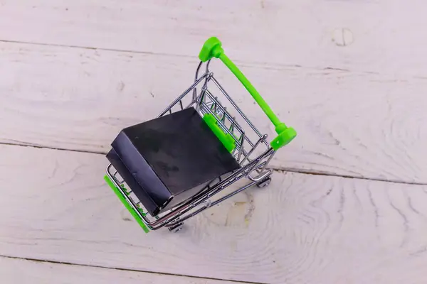 Carrito con caja negra sobre fondo de madera blanco —  Fotos de Stock