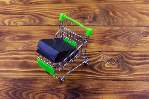 Carrito con caja negra sobre fondo de madera —  Fotos de Stock