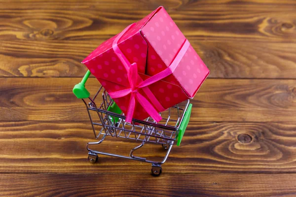 Carrito de compras con caja de regalo grande sobre fondo de madera —  Fotos de Stock