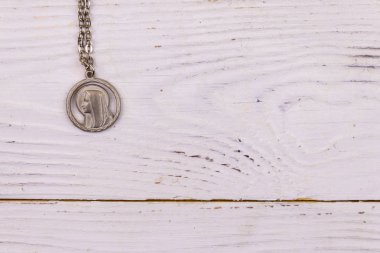 Beyaz ahşap arka plan üzerinde Bakire Meryem kolye. Üst görünüm, kopyalama alanı