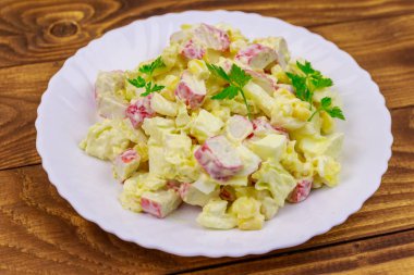 Yengeç saplı salata, tatlı mısır, Çin lahanası, yumurta ve mayonez ahşap masada.