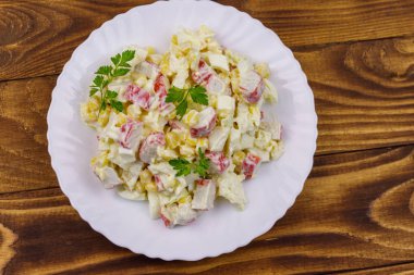 Yengeç saplı salata, tatlı mısır, Çin lahanası, yumurta ve mayonez ahşap masada.